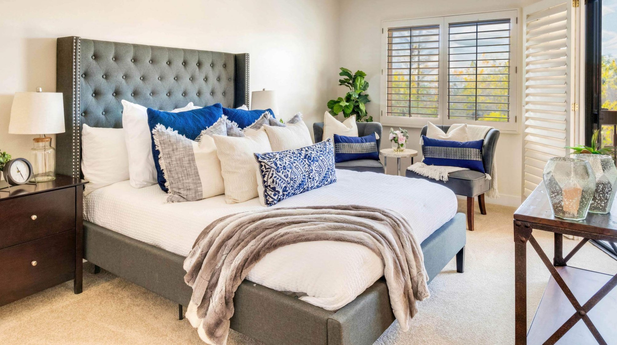 Bedroom with dark gray tufted headboard and dark wood accent furniture in an independent living model home